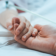 Two people holding hands in hospital bed